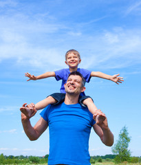 Happy father with son outdoors against sky