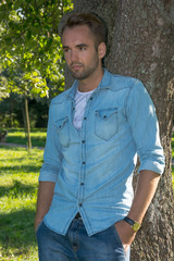 Young man standing at tree in park in summer