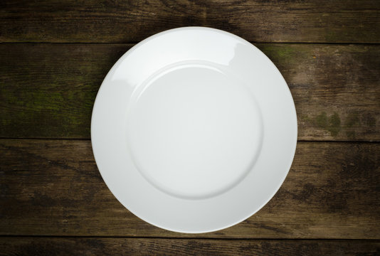 Empty white plate on wooden table