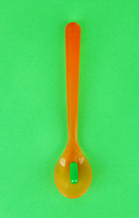 Plastic spoons with color pills on green background