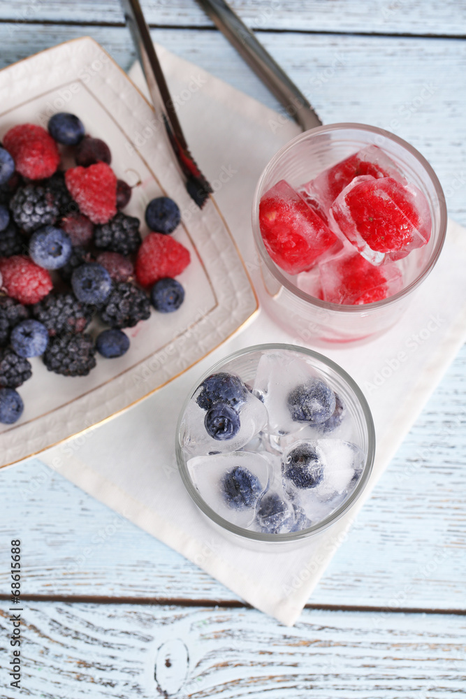 Wall mural Frozen berries and ice cubes with mint leaves, raspberry and