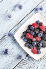 Frozen berries on color wooden background
