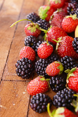 Blackberries and strawberries on wooden background