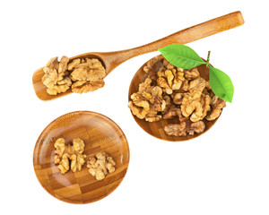 Handful of walnuts in wooden bowls, scoop and green leaves isola