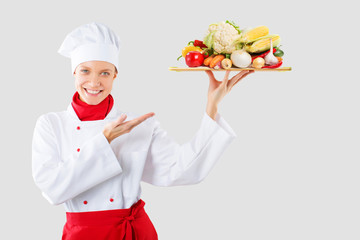 cook holds in one hand a wooden tray vegetables