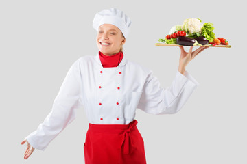 cook holds in one hand a wooden tray vegetables