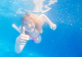 Fototapeta na wymiar Portrait of a cute little girl swimming underwater