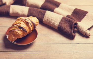 french croissant and scarf on a wooden table