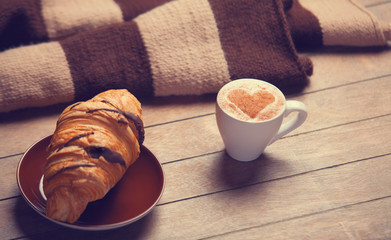 french croissant and cup of coffee on a wooden table