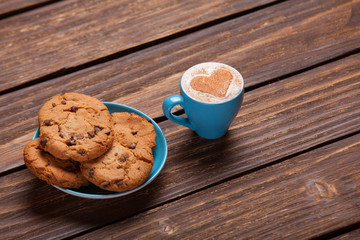 Cookie and cup of coffee on wooden table.