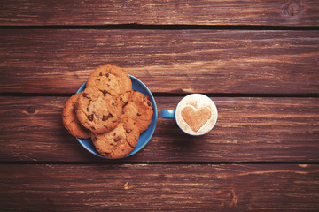 Cookie and cup of coffee on wooden table.