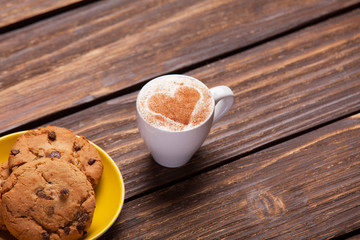 Cookie and cup of coffee on wooden table.