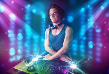 Dj mixing music in a club with blue and purple lights