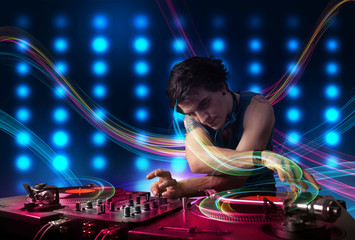 Young Dj mixing records with colorful lights