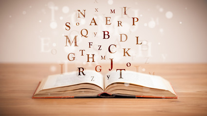 Opened book with flying letters