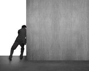 businessman pushing concrete wall away