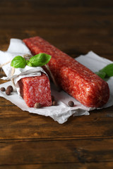 Tasty salami sausage and spices on wooden background