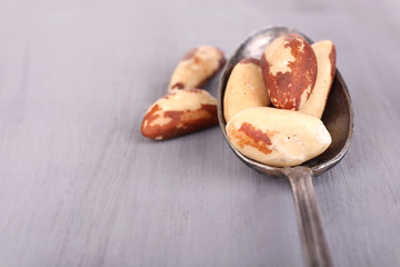 Vintage spoon with tasty brasil nuts on wooden background