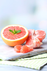 Ripe grapefruits on cutting board, on wooden background