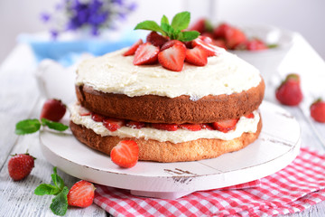 Fototapeta na wymiar Delicious biscuit cake with strawberries on table close-up