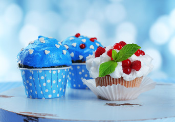 Tasty cupcakes on table, on bright background