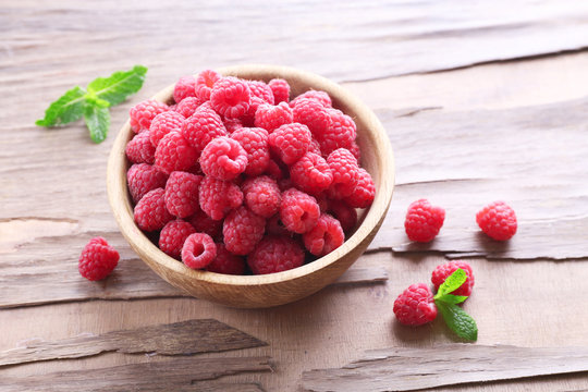 Ripe sweet raspberries in bowl on table close-up