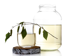 Glass and large flagon of fresh birch sap isolated on white