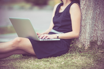 Beautiful young woman using laptop in park