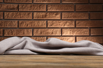 Wooden table with cloth on wall background