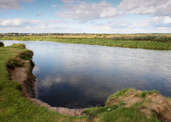 View to river with reflections and blue cloudy sky
