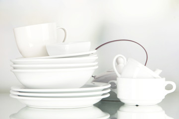 Fototapeta na wymiar White crockery and kitchen utensils, on light background