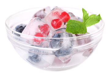 Ice cubes with forest berries, in glass bowl, isolated on white