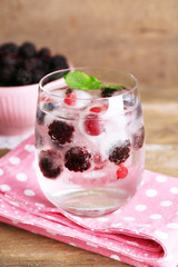 Cold cocktail with forest berries, frozen in ice cubes and