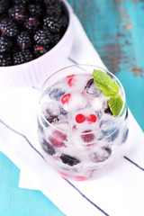 Cold cocktail with forest berries, frozen in ice cubes and