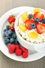 Cottage cheese with fruits and berries in bowl on table