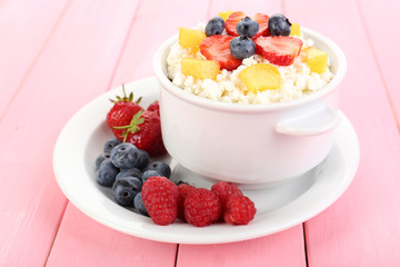 Cottage cheese with fruits and berries in bowl on wooden table