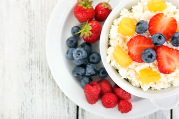Cottage cheese with fruits and berries in bowl on wooden table