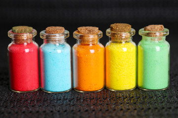 Bottles with colorful dry pigments on dark background