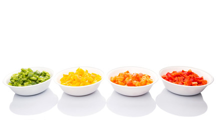 Colorful chopped capsicums in white bowls over white background