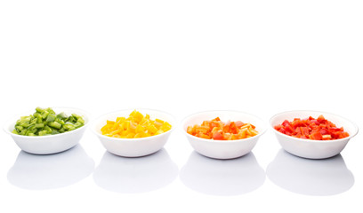 Colorful chopped capsicums in white bowls over white background