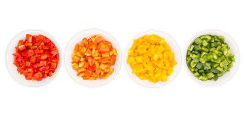 Colorful chopped capsicums in white bowls over white background