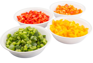 Colorful chopped capsicums in white bowls over white background