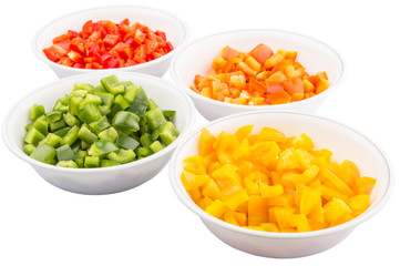 Colorful chopped capsicums in white bowls over white background