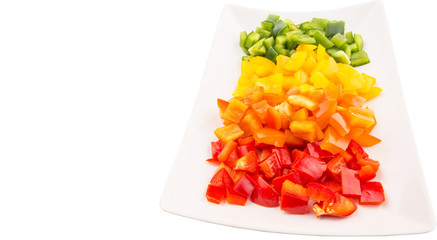 Colorful chopped capsicums in a plate over white background 