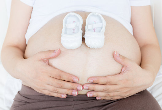 Pregnant belly with a pair of white shoes