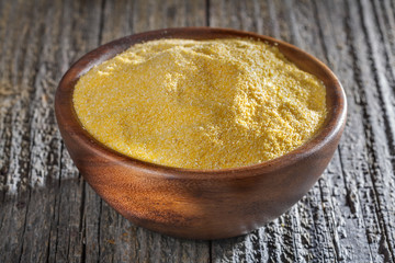 corn grits polenta in a wooden bowl on old wooden table
