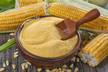 corn grits polenta in a wooden bowl on old wooden table - obrazy, fototapety, plakaty