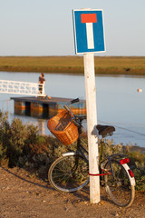 Bycicle leaning on a dead end sign by the sea