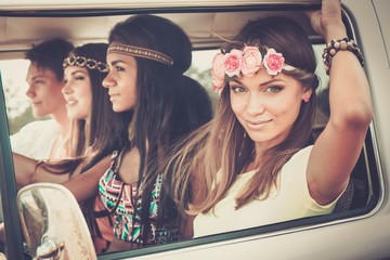 Multi-ethnic hippie friends in a minivan on a road trip - obrazy, fototapety, plakaty