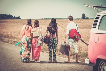 Multi-ethnic hippie friends with guitar and luggage
